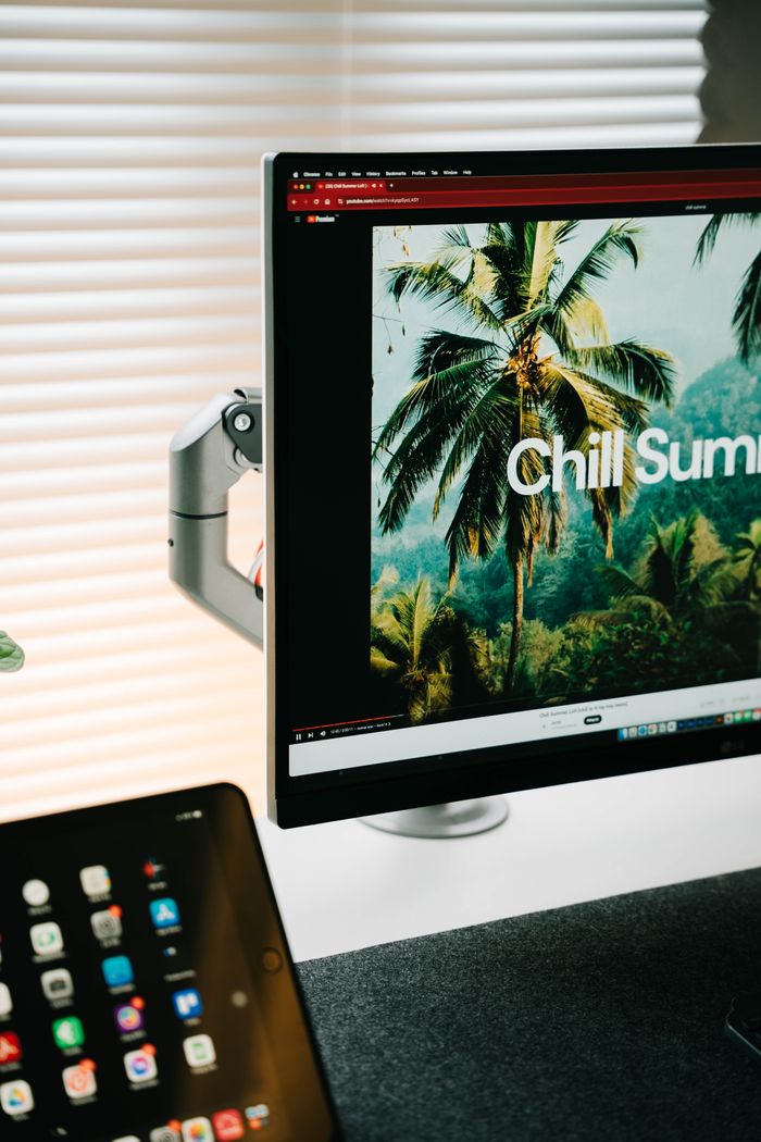 Trendy workspace with a monitor displaying tropical summer vibes, perfect for creative inspiration.