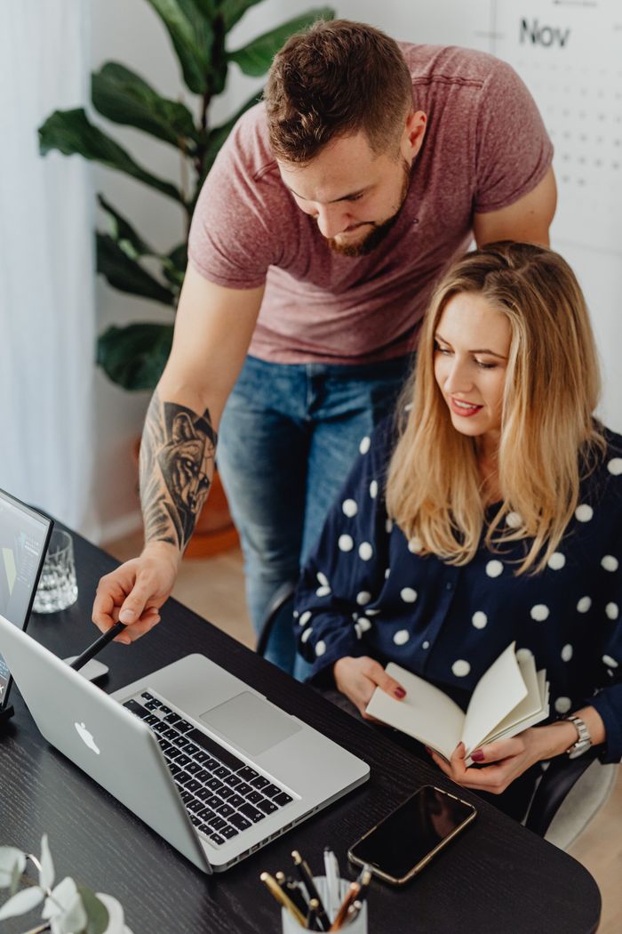Man and woman working together on a project with a laptop. Office environment with indoor plants.