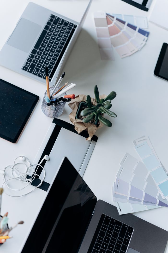 Home Top view of an organized workspace featuring a laptop, succulent plant, and office supplies on a white desk.